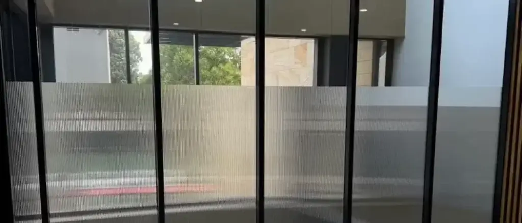 "Commercial office foyer entrance on the Sunshine Coast featuring stylish reeded decorative privacy film on glass panels, offering visual separation without blocking natural light."
